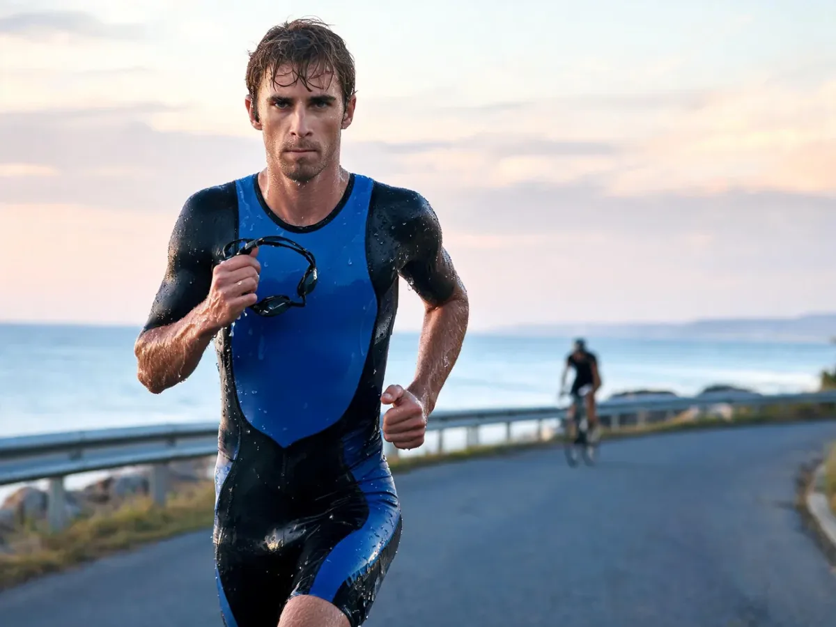 Triathlonista na trasie Ironmana biegnie wzdłuż wybrzeża o świcie, zmęczony po pływaniu, ale skoncentrowany na celu